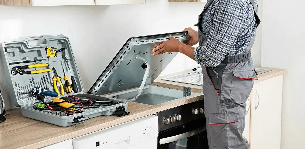 Handyman repairing a cooktop and checking wiring connections in Dover, DE