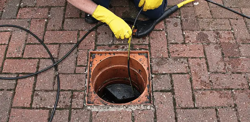 Drain cleaning technician using a drain snake to clear a clogged drain in Dover, DE
