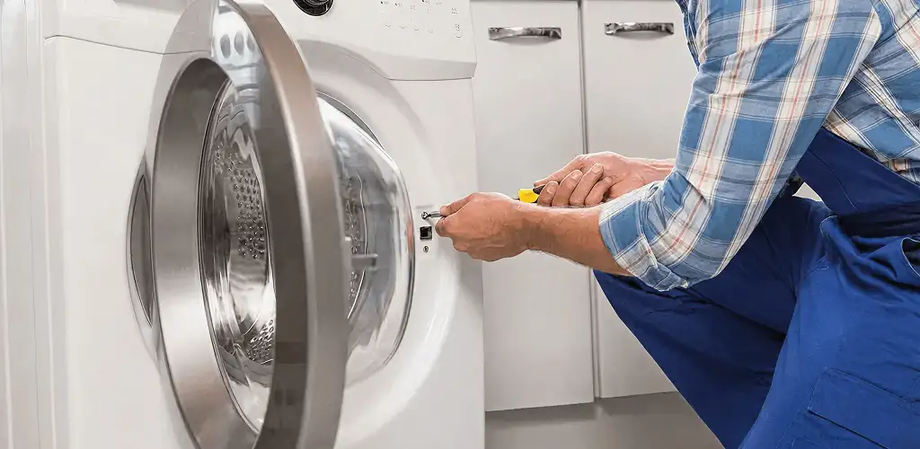 Handyman repairing a clothes dryer and checking electrical connections in Dover, DE