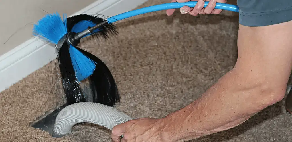 Dryer vent cleaning technician brushing lint from a vent line in Dover, DE