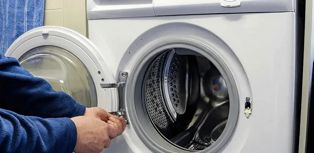 Washing machine repair handyman checking a front-load washer door and latch in Dover, DE
