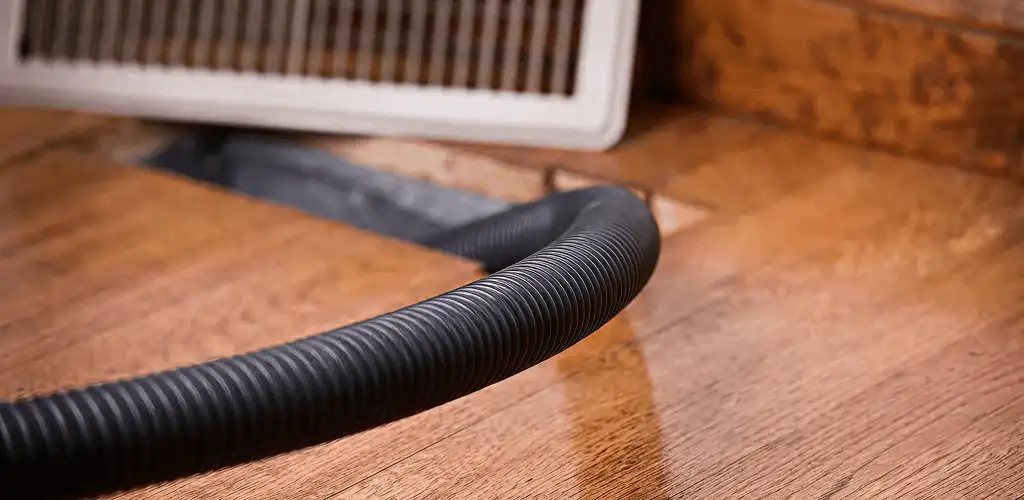 Air duct cleaning hose inserted into a floor vent for ductwork cleaning in Dover, DE