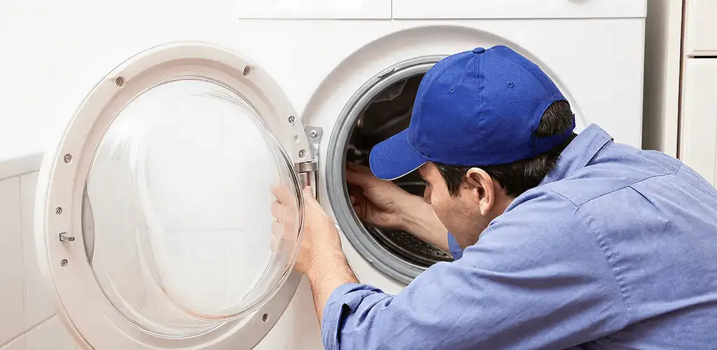 Washing machine repair handyman inspecting a front-load washer drum in Dover, DE