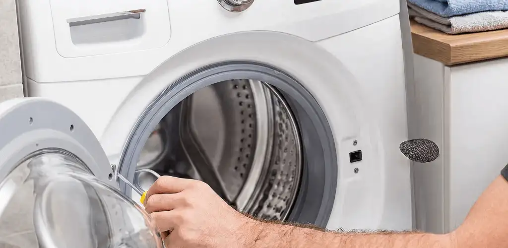 Handyman repairing a front-load washing machine and inspecting the drum in Dover, DE