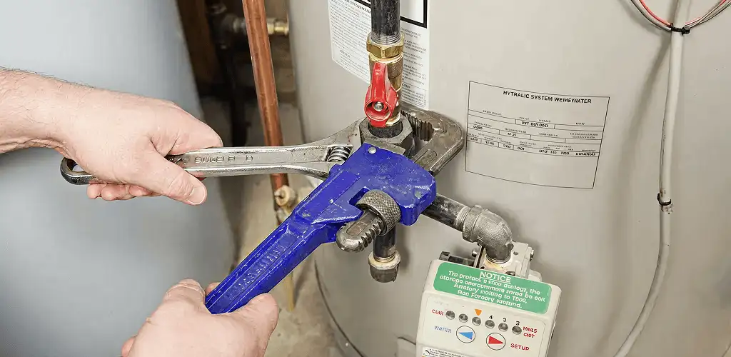 Water heater repair technician tightening the shutoff valve and supply line in Dover, DE